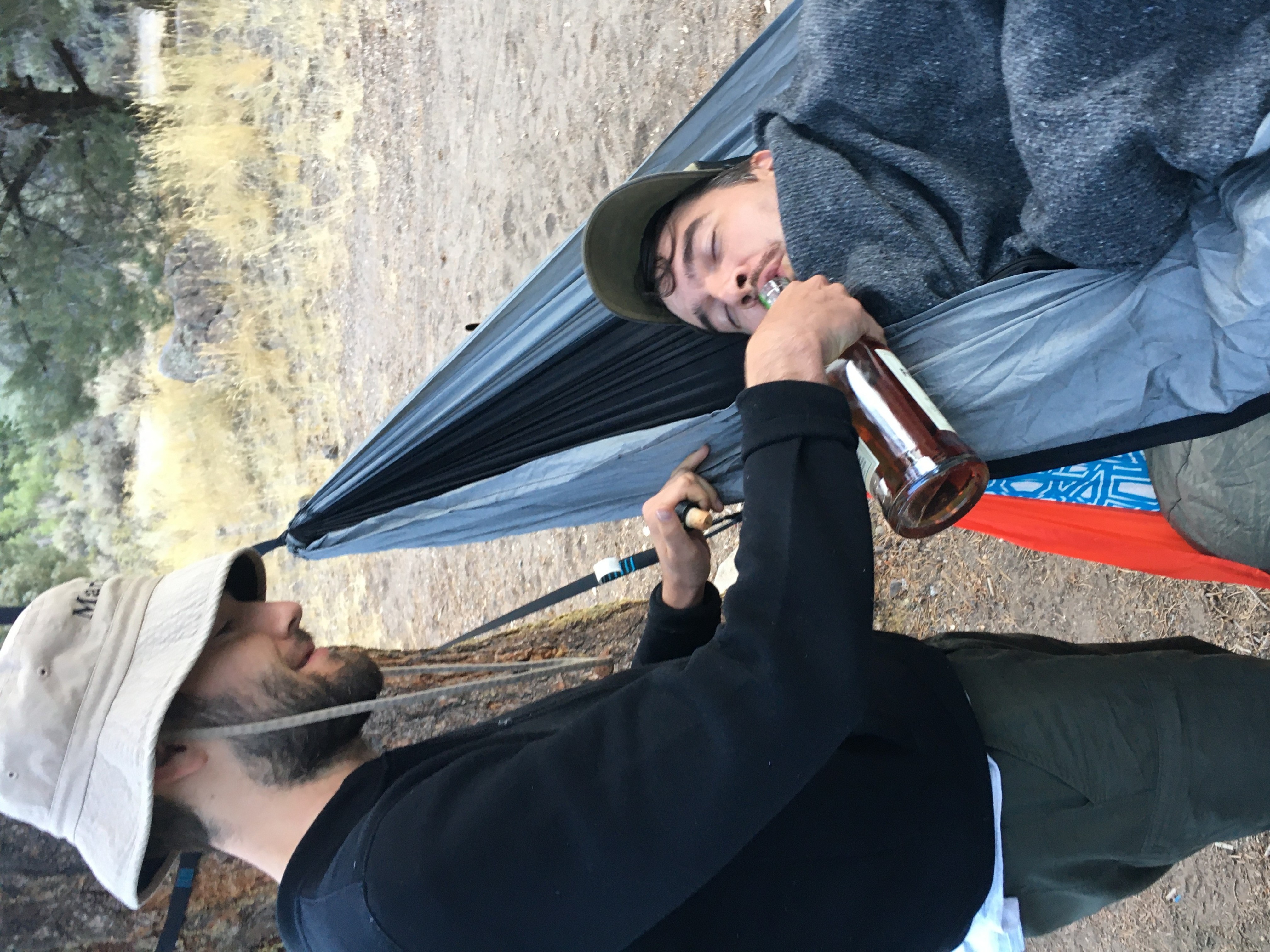 An early morning photo of me pouring some whiskey into my brother's mouth as he lays in a hammock